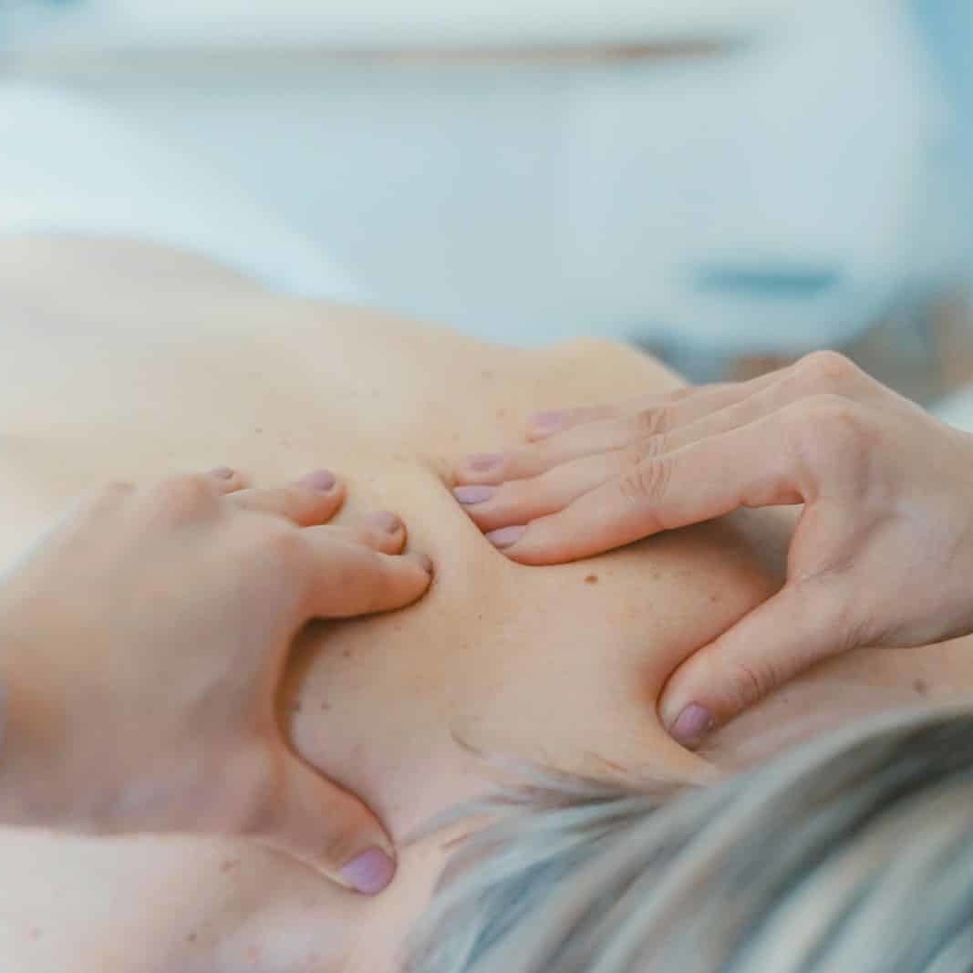 person massaging the back of a woman